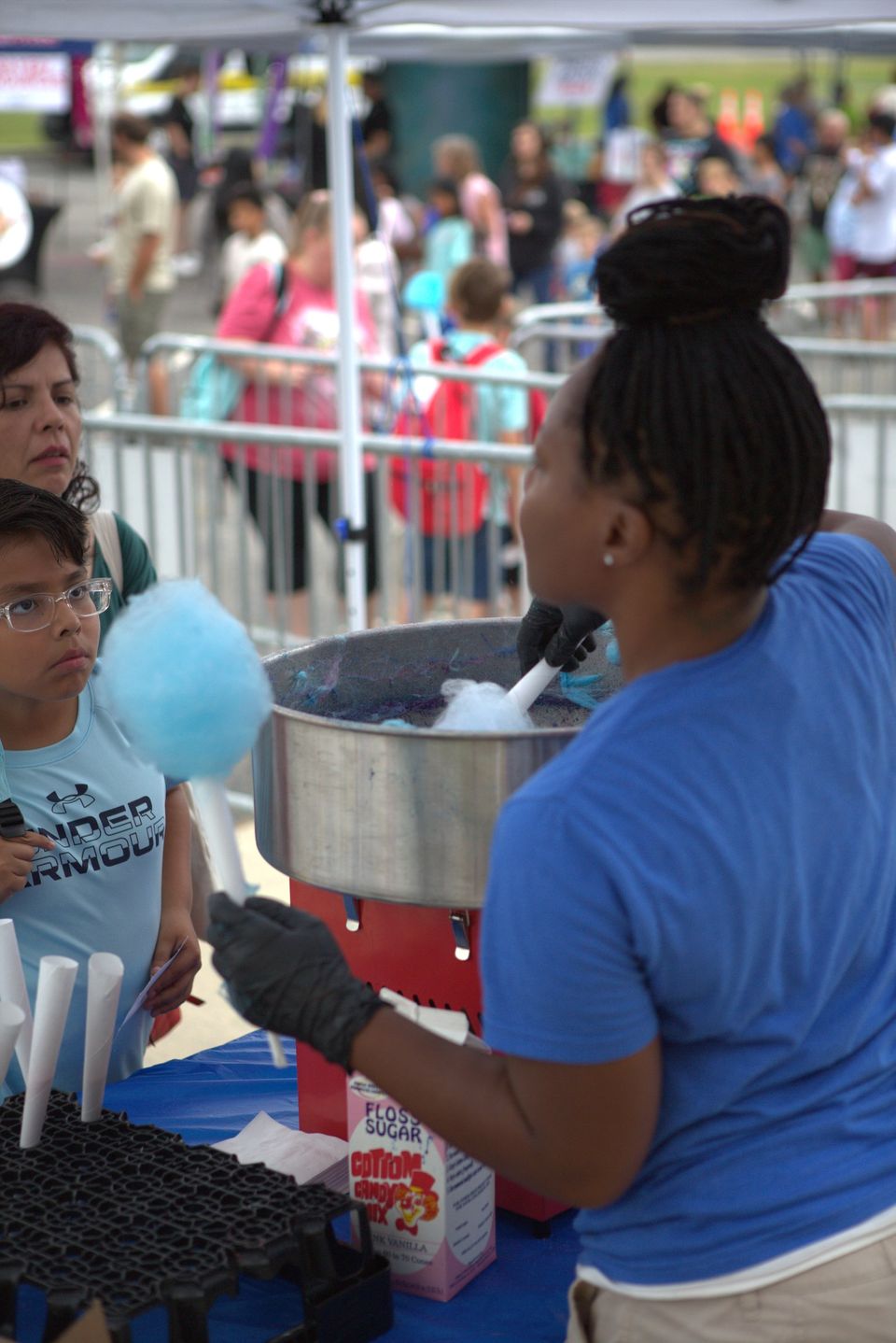 A volunteer spins blue cotton candy for children at a Deliver Hope event.