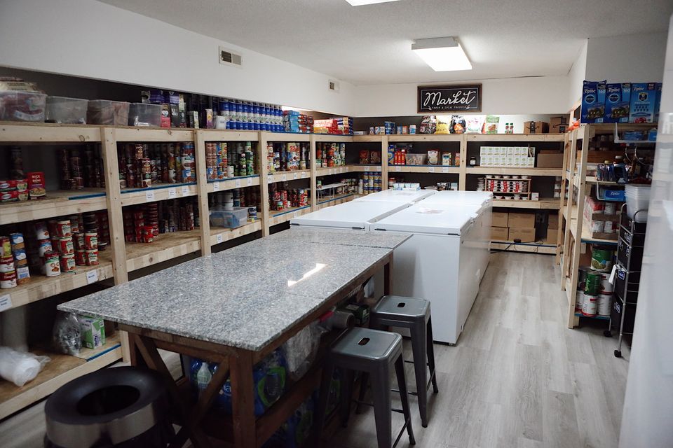 The Hope Center Market: wooden shelves of canned and boxed food, chest freezers, and a granite prep table.