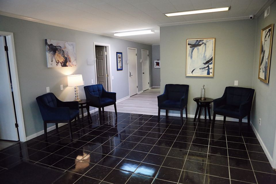 The Hope Center waiting area with navy armchairs, a lit lamp, and abstract art on grey walls.
