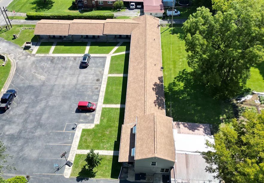 Aerial view of the L-shaped Hope House building, a former motel, with its parking lot and lawn.