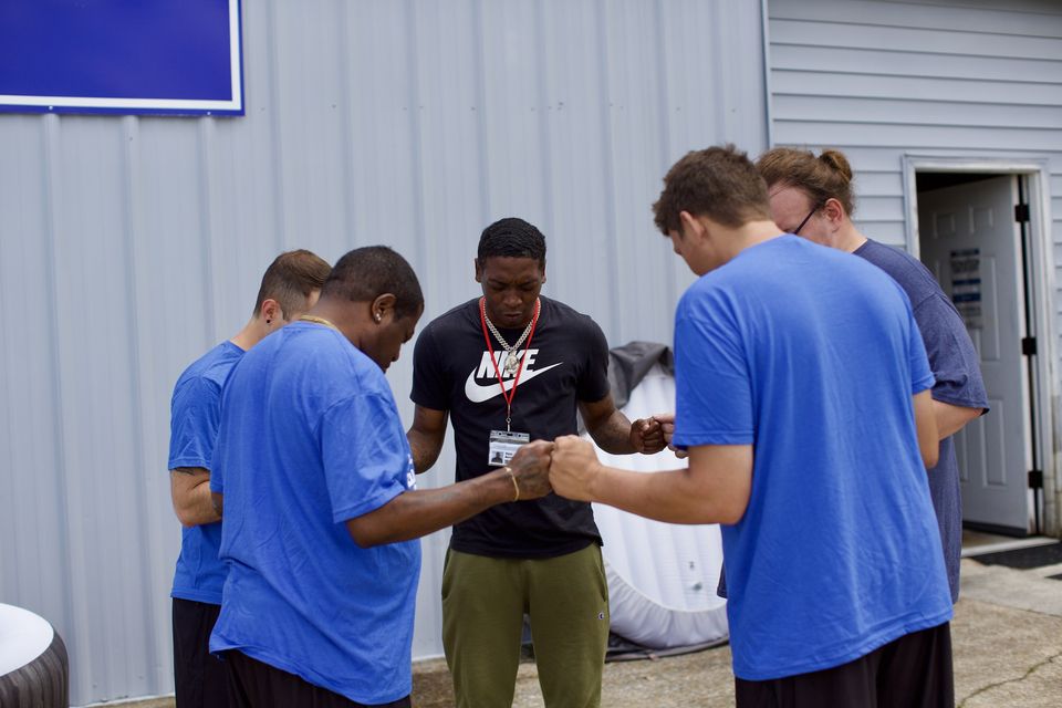 Hope House residents stand in a circle with heads bowed in prayer before a baptism.
