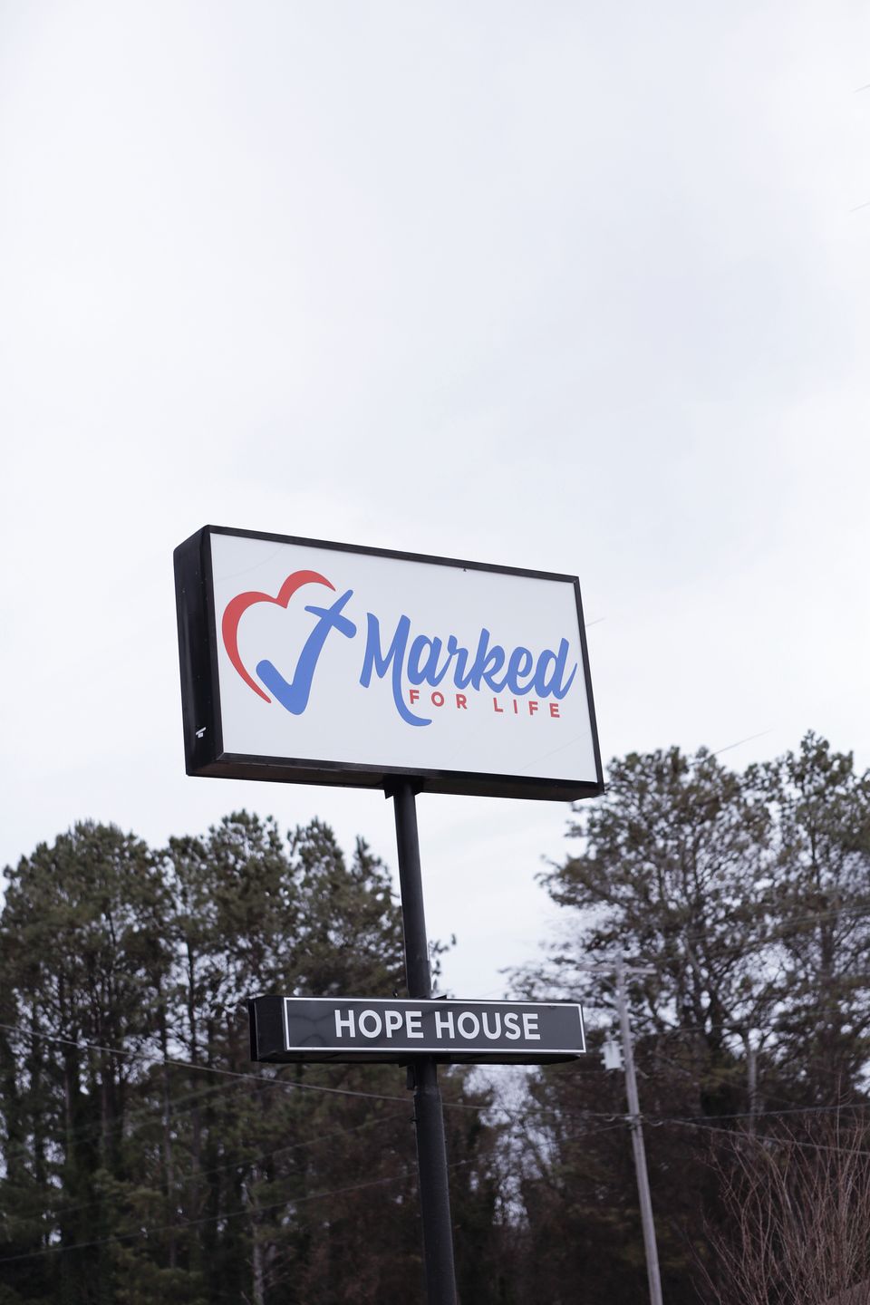 The Marked For Life road sign with a Hope House panel beneath it, against a grey winter sky.