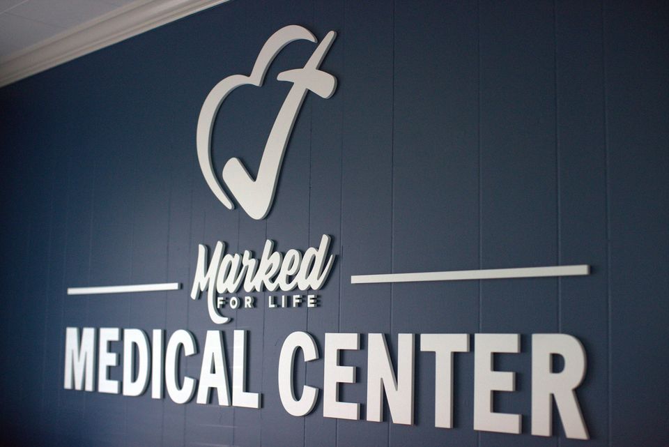 Dimensional white letters reading Marked For Life Medical Center on a navy wall.